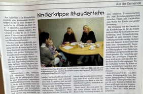 Drei Erwachsene und ein Kleinkind sitzen an einem runden Holztisch mit Teegeschirr in einem hellen Raum mit weißer Wand und Fenster