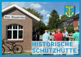 Historische Schutzütte aus Backstein mit Schild 'Historische Schutzhütte' und Fahrrad davor, Menschen im Hintergrund