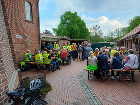 Gruppe von Menschen mit Fahrrädern und gelben Warnwesten vor einem Gebäude