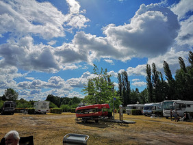 Wolkenhimmel über einem Wohnmobilstellplatz und Kanus im Hintergrund