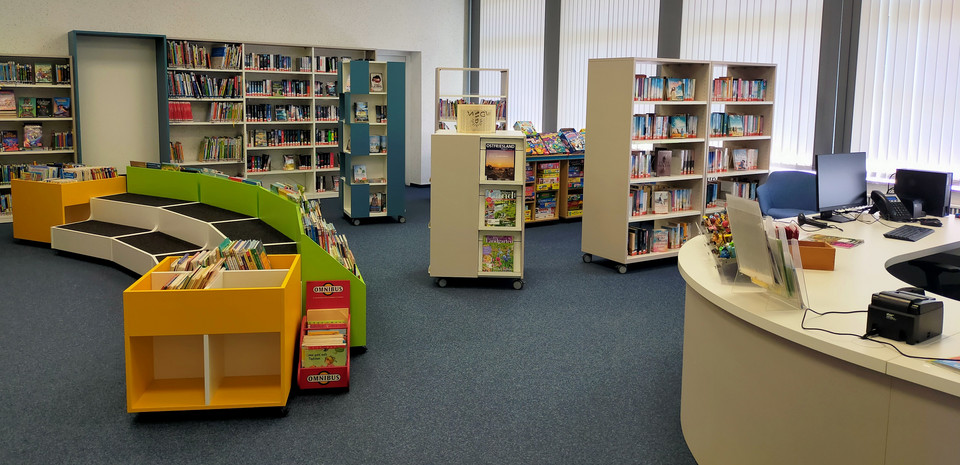 Offener Raum mit bunten Bücherregalen