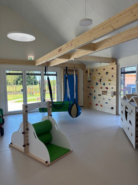 Bewegungsraum für Kinder mit Spielgeräten und großen Fenstern