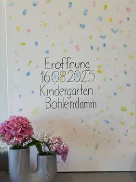 Leinwand mit der Wand mit der Aufschrift 'home sweet home' in dekorativem Schriftzug über einem Tisch mit rosa Blumen in einer Vase